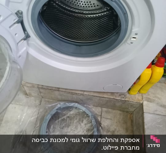 מכונת כביסה פתוחה עם חלק חילוף על הרצפה